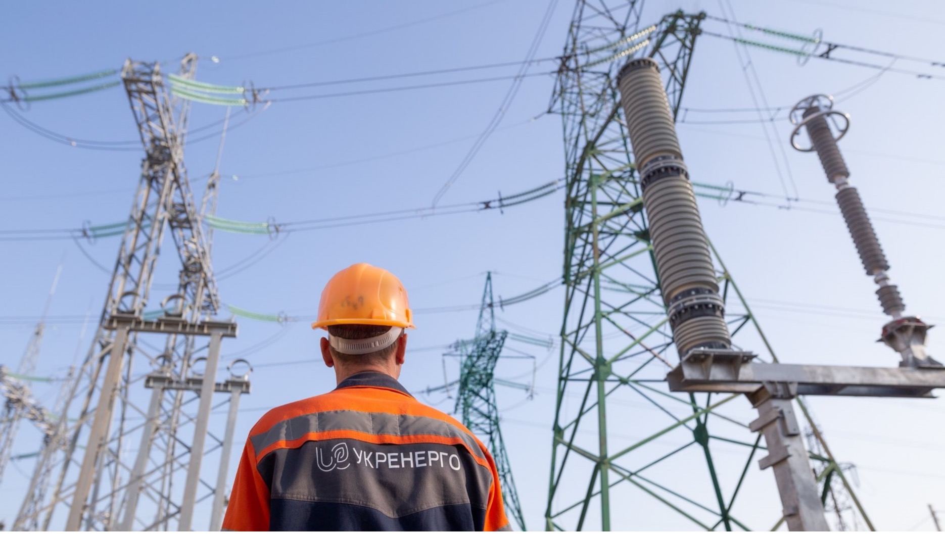 Utility worker standing in front of transmission towers